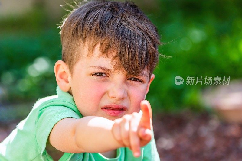 一个哭闹的白人小男孩指着摄像机