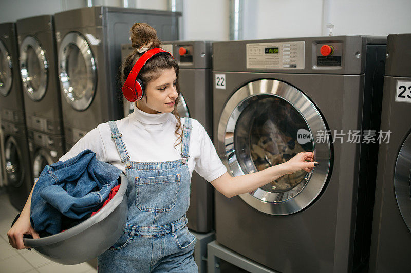 一个年轻的白人女人在自助洗衣店洗衣服