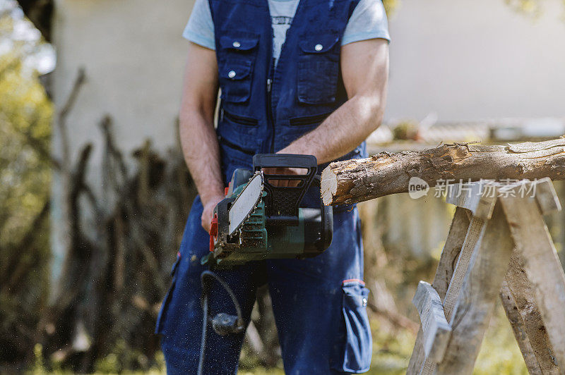一个人用电锯在砍树干