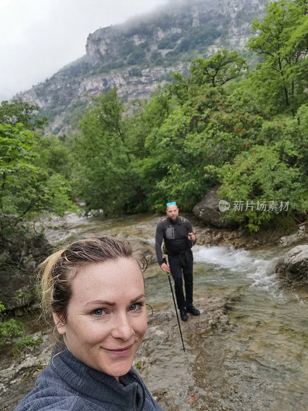 一对夫妇在徒步旅行中穿越小溪的自拍