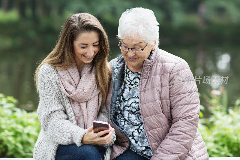 老女人和孙女在看智能手机