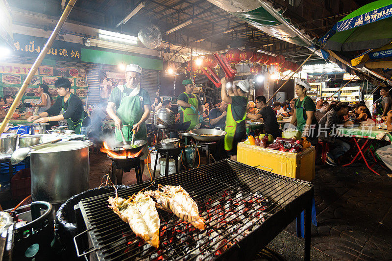 2019年12月28日，在泰国首都曼谷，人们在曼谷唐人街的街边小摊上烤鱼等菜肴