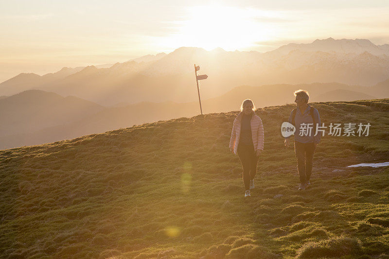 夫妇走在高高的草地上，路标