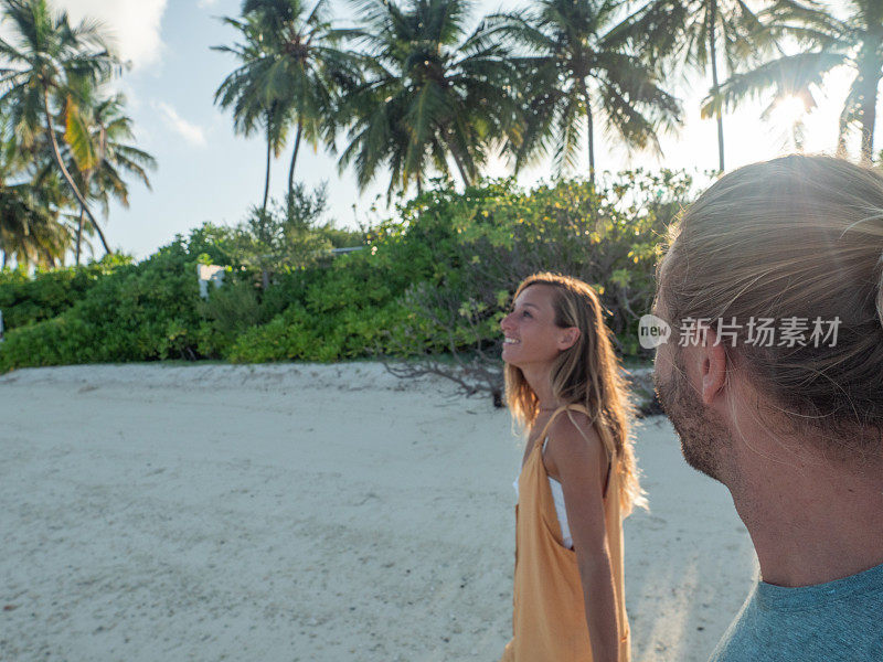 在热带海滩上牵着手的夫妇的侧视图