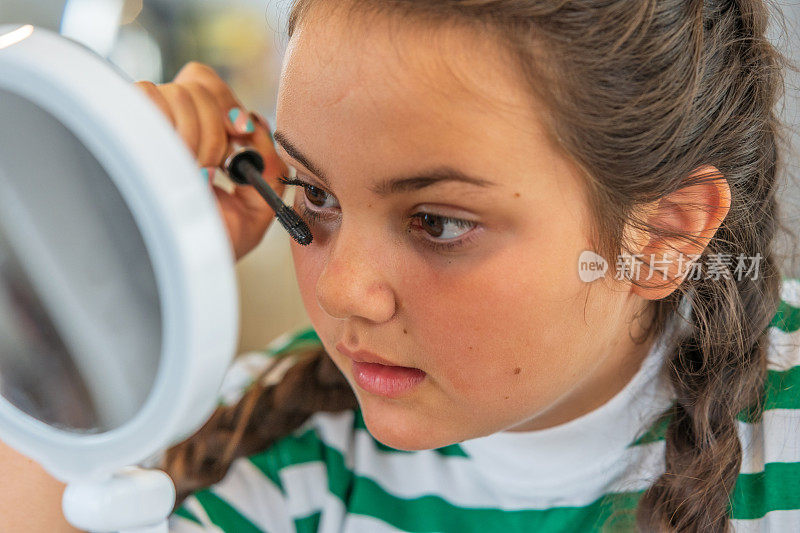 一个十三岁的女孩正在往睫毛上涂睫毛膏