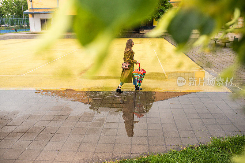 一个年轻女子在雨天走过水坑