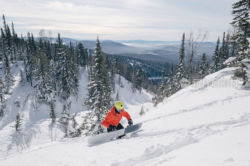 冬季阳光明媚的日子里，滑雪板自由骑手爬山