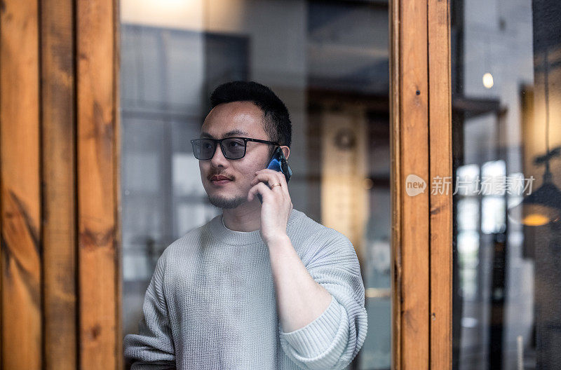 亚洲商人在一家咖啡馆的窗口打电话