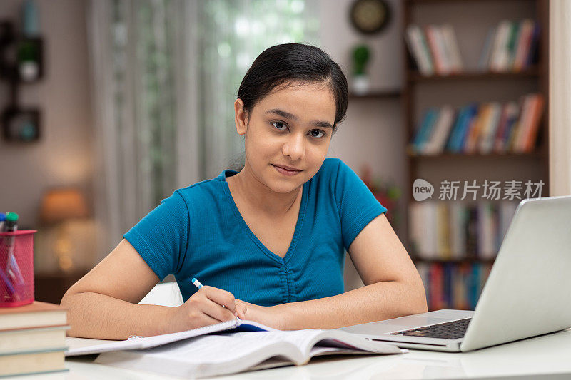 一个十几岁的女孩在家里学习的照片:-库存照片