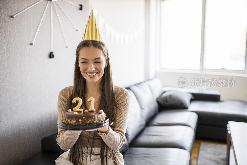 年轻漂亮的女人在家里用巧克力蛋糕庆祝她21岁的生日