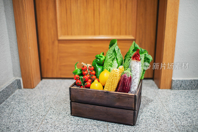 食品购物箱站在房子或公寓的门口。蔬菜水果在检疫和自我隔离期间交付