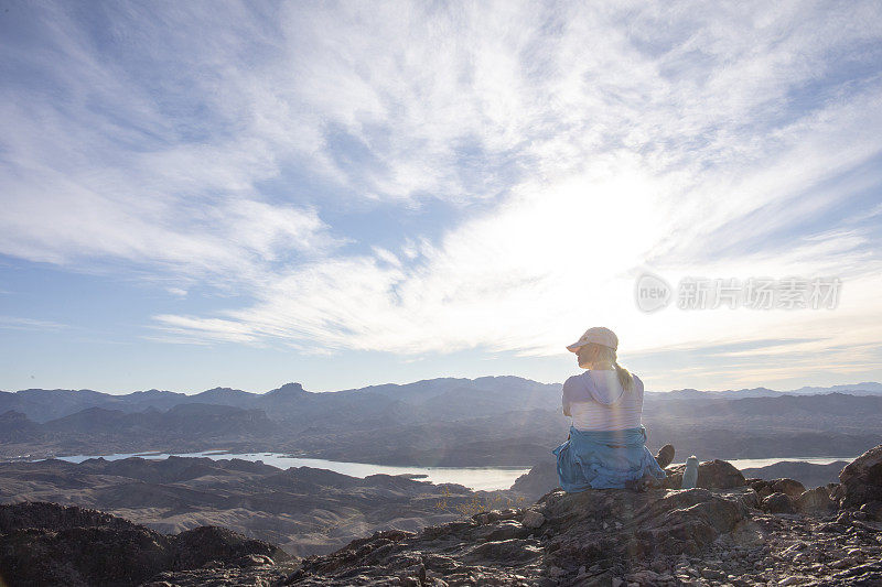 女徒步旅行者在阳光明媚的山脊上休息