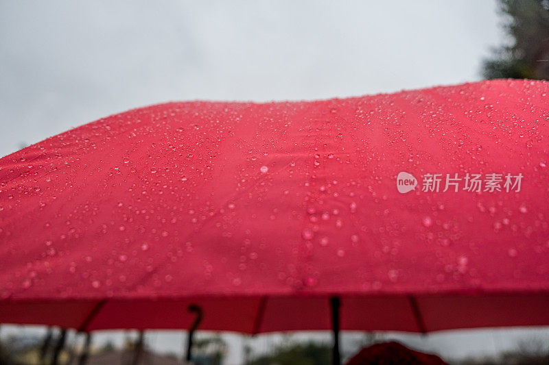 一个人撑着一把红伞在雨天行走