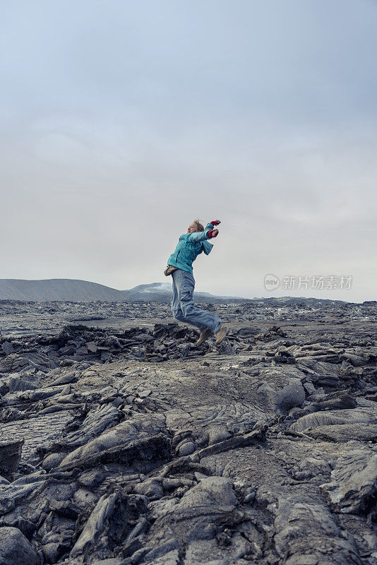 女人们在Fagradalsfjall火山的黑色熔岩上跳跃