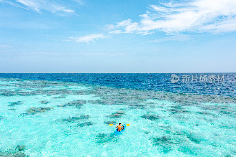 在热带海洋上划着皮艇的年轻人