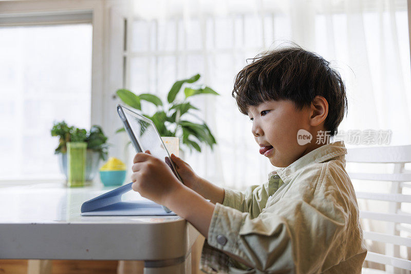 亚洲小男孩在数字平板电脑上玩游戏