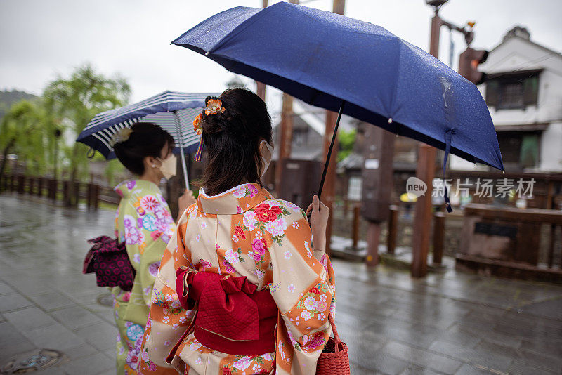 穿着和服的日本女性朋友在雨天参观日本传统村庄的背影