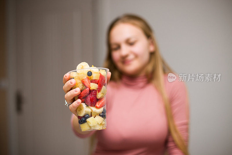 用塑料杯装水果沙拉的小女孩