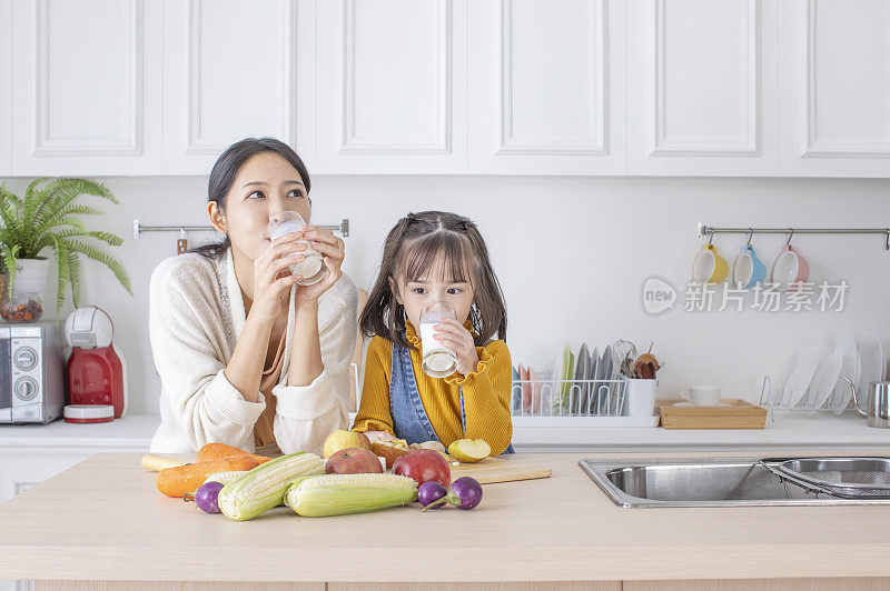美女妈妈和可爱女儿在厨房喝牛奶