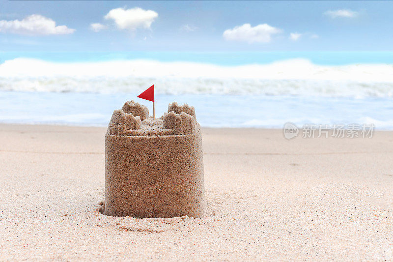 红色旗帜的沙滩城堡，热带沙质的夏季海洋海滩，美丽的蓝天为背景，轻松的户外度假在海滩岛。