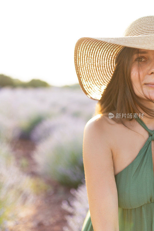 年轻女子穿着夏装，戴着太阳帽，透过薰衣草田的背影感到幸福