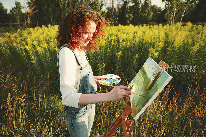 年轻女子在户外画风景画。