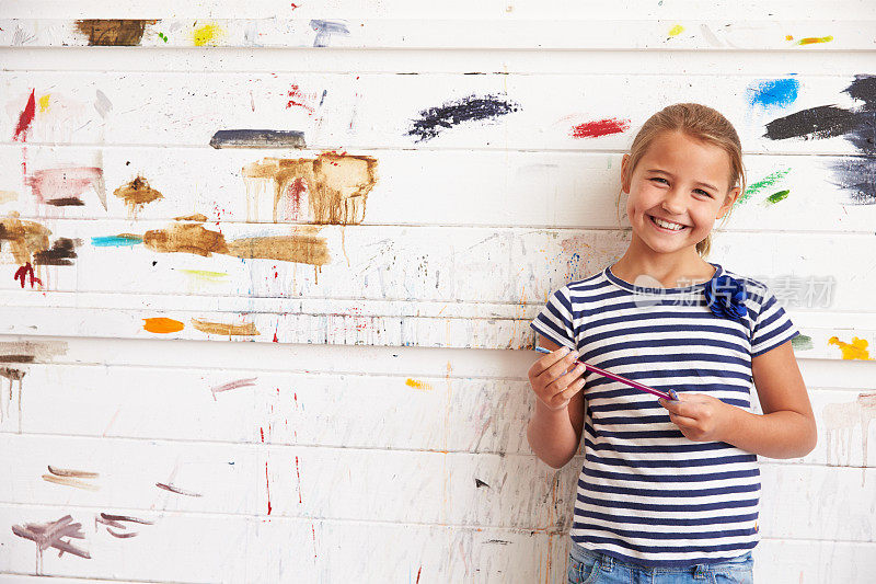 在艺术工作室的女孩肖像在油漆覆盖的墙壁上