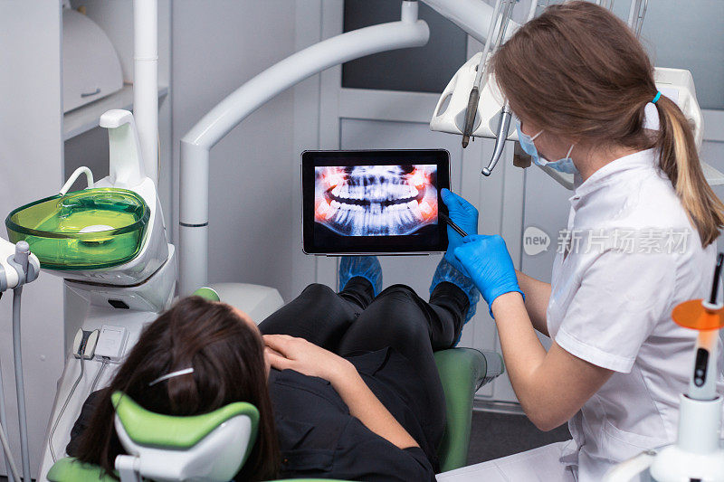 牙科医生在平板上展示x光的牙齿