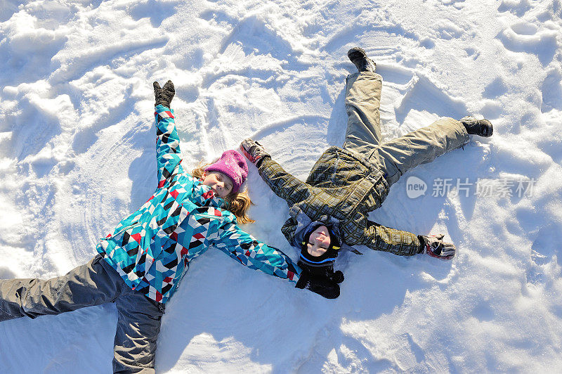 女孩和男孩躺在雪地上