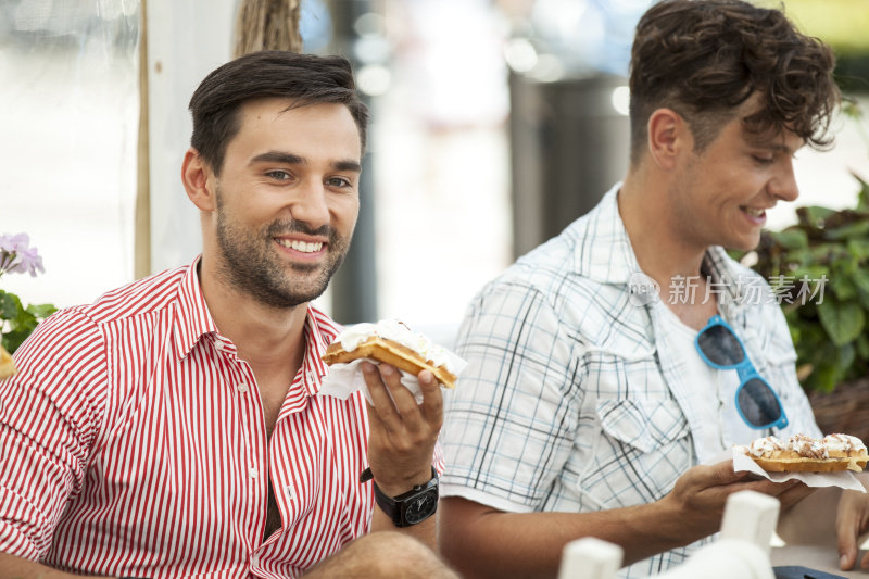 在路边咖啡馆吃比利时华夫饼的男人