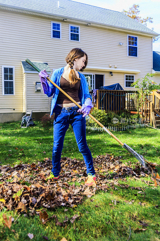 十几岁的女孩正在清理后院的落叶