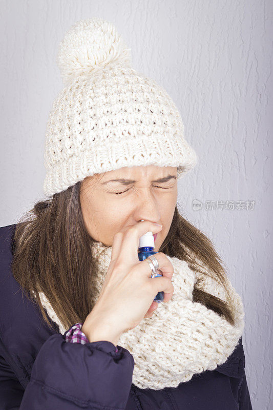 一个年轻女人在用喷喉剂。