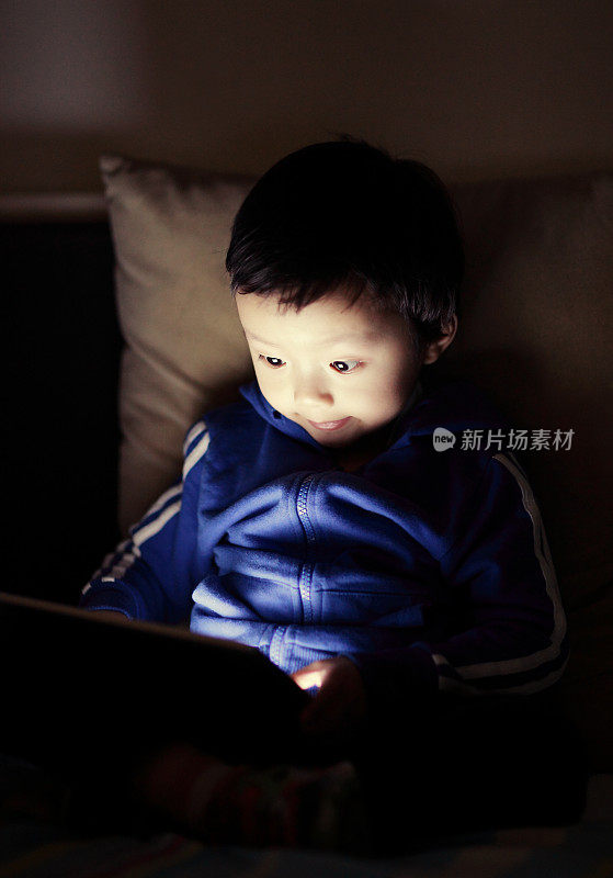 小男孩在床上用平板电脑