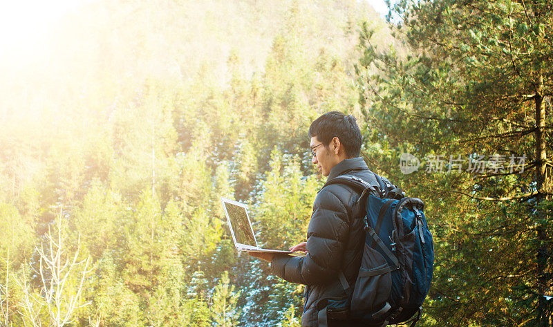 徒步旅行者在森林中使用笔记本电脑