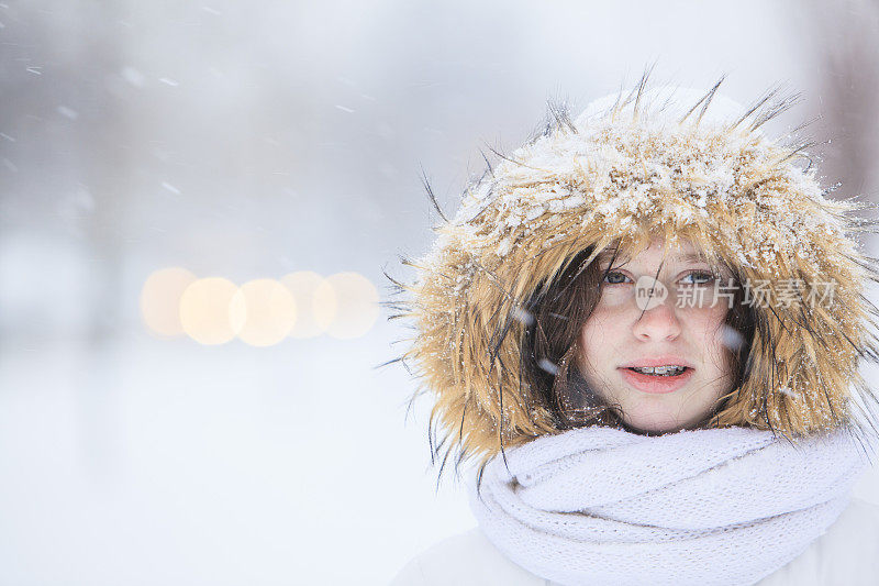 雪下穿着白色夹克的漂亮少女