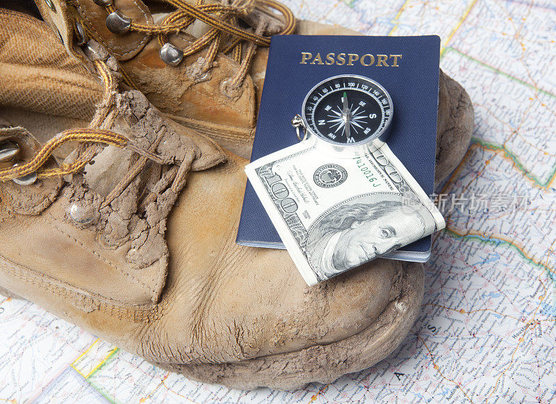 护照，指南针，美元和徒步靴在地图的背景