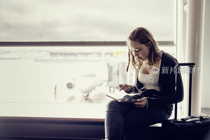 在机场等待的旅行女孩带着平板电脑，复印空间。