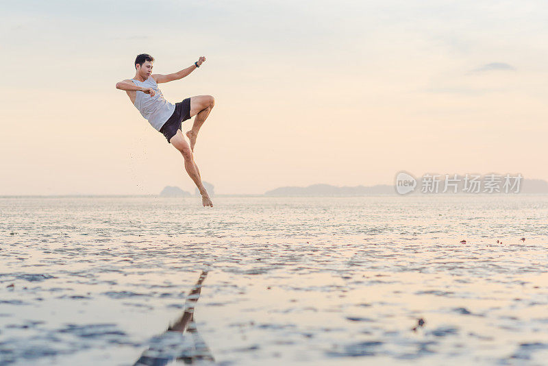 年轻的亚洲男子训练空手道和踢拳击在海滩