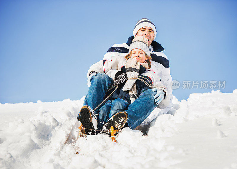 父亲和儿子在冬天拉雪橇。
