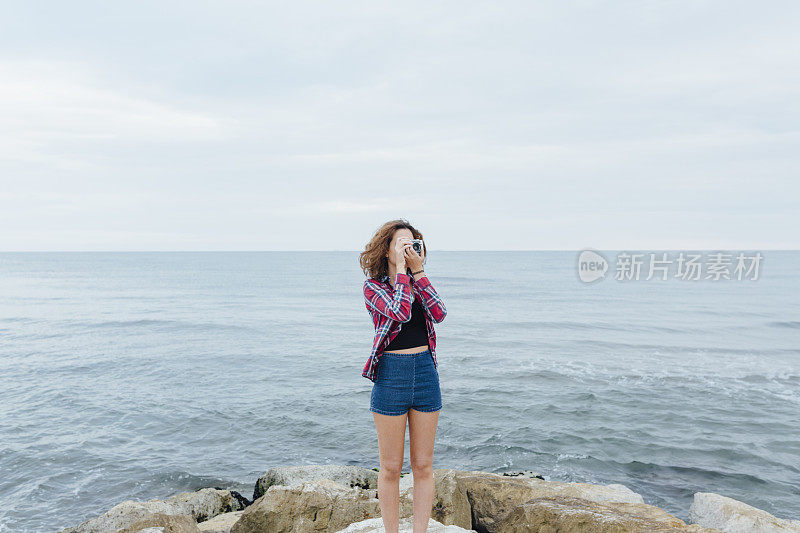 女孩在海上用胶卷相机拍照