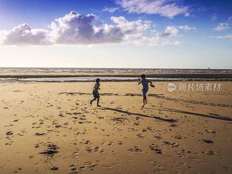 英国默西塞德郡，男孩们在海滩上奔跑