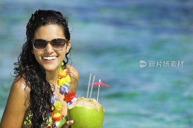 年轻女子在热带海滩清爽椰子饮料