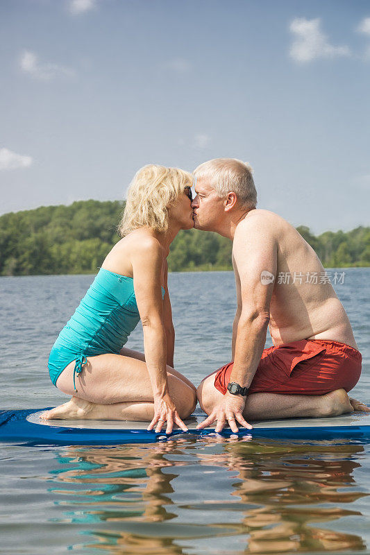 一对金发情侣在冲浪板上接吻