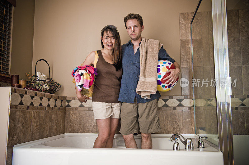 穿着沙滩服的男人和女人站在浴室的浴缸里