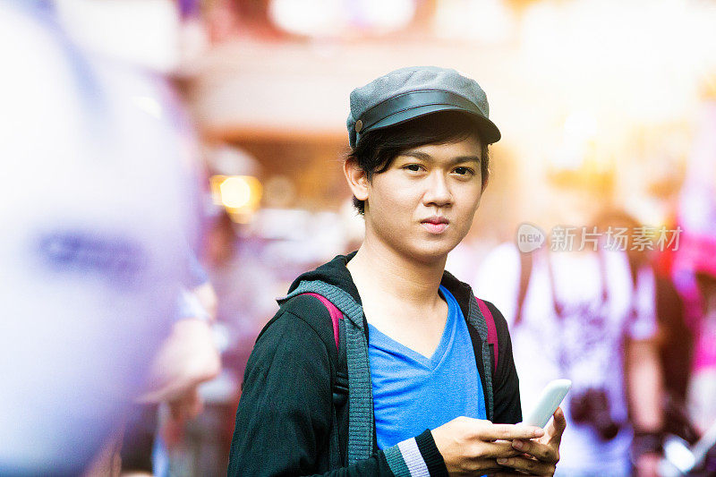 严肃的男性印尼青少年城市肖像与翻盖手机