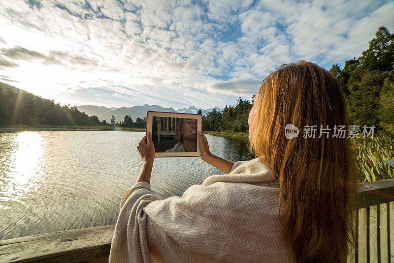 日出时分，一名女性用平板电脑拍摄风景