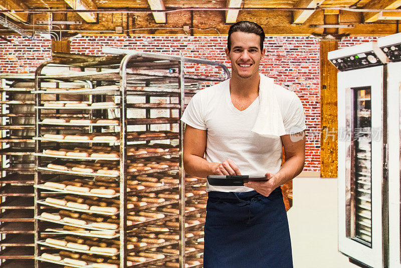 微笑的面包师在面包店使用平板电脑