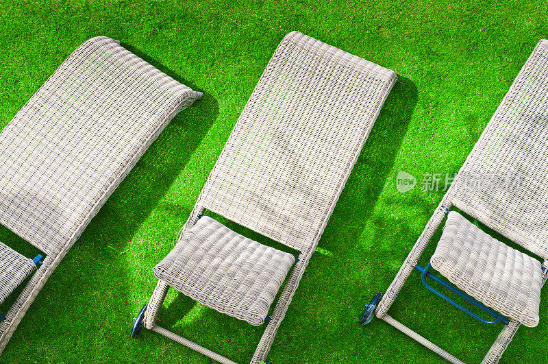 绿色草坪上放着三张躺椅