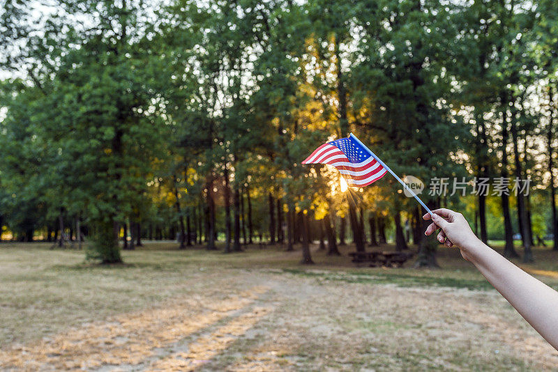 在夕阳下高举美国国旗