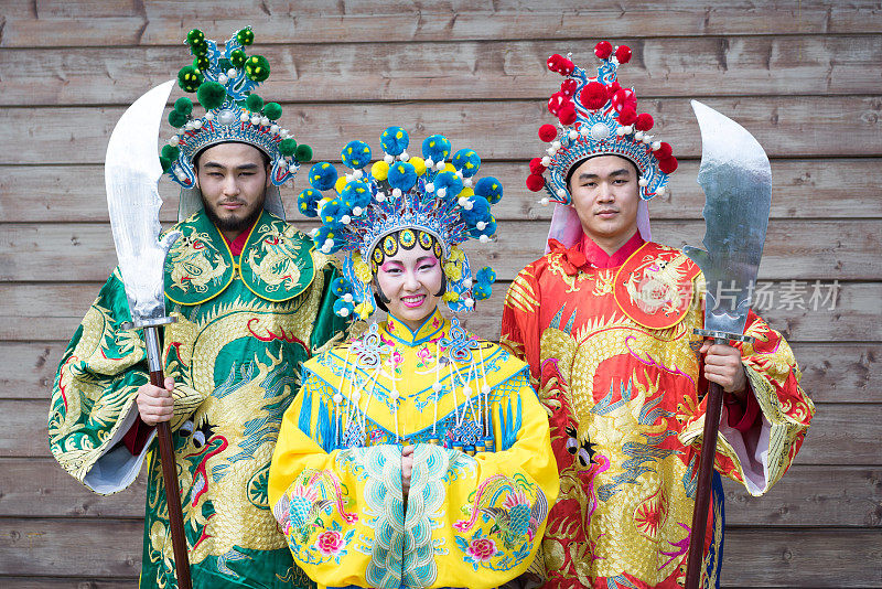 一组三个亚洲人男女站成一排，穿着中国传统服装在户外打招呼